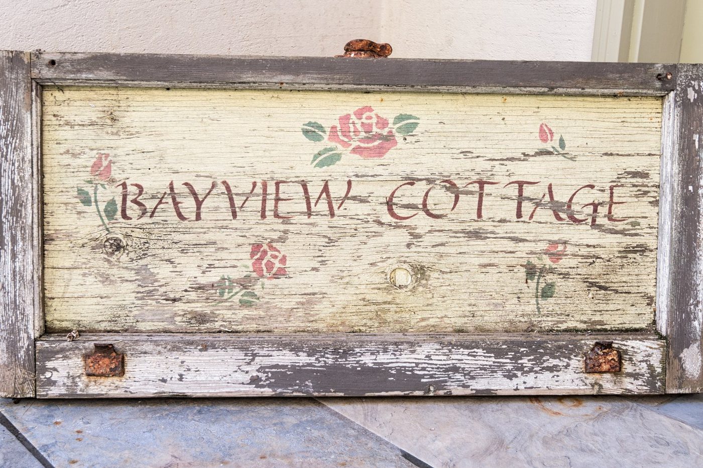 The hand-painted Bayview Cottage sign, weathered and set with roses